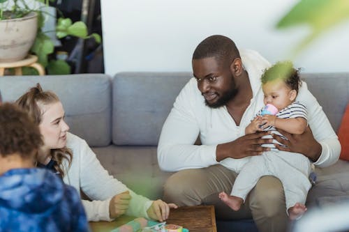 Free Crop multiracial family talking on sofa in house room Stock Photo