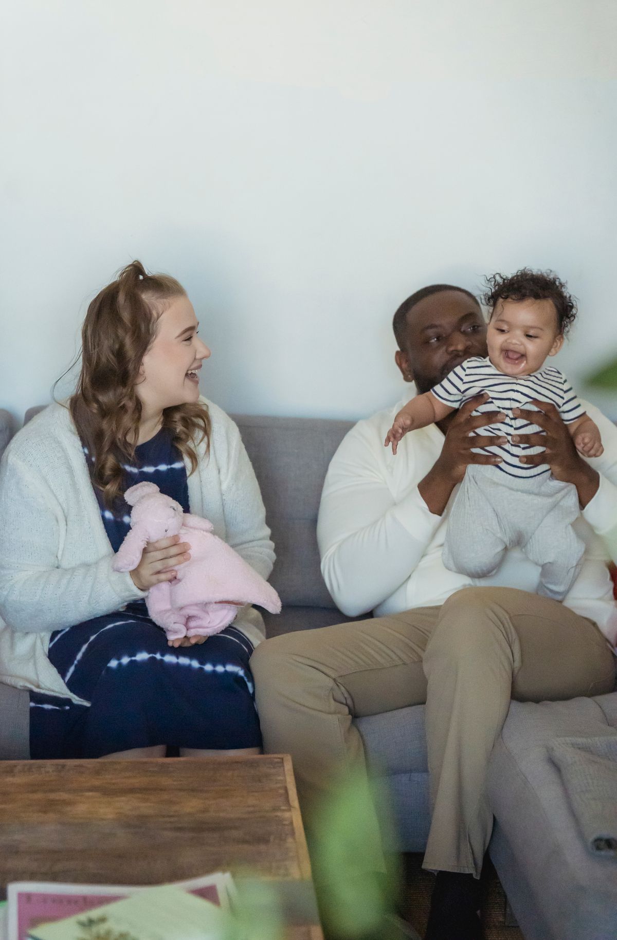Família multirracial feliz no sofá representando proteção jurídica e vínculo afetivo familiar