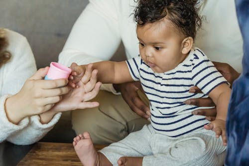 Free Crop anonymous multiethnic family interacting with cute little child while spending time at table in house Stock Photo
