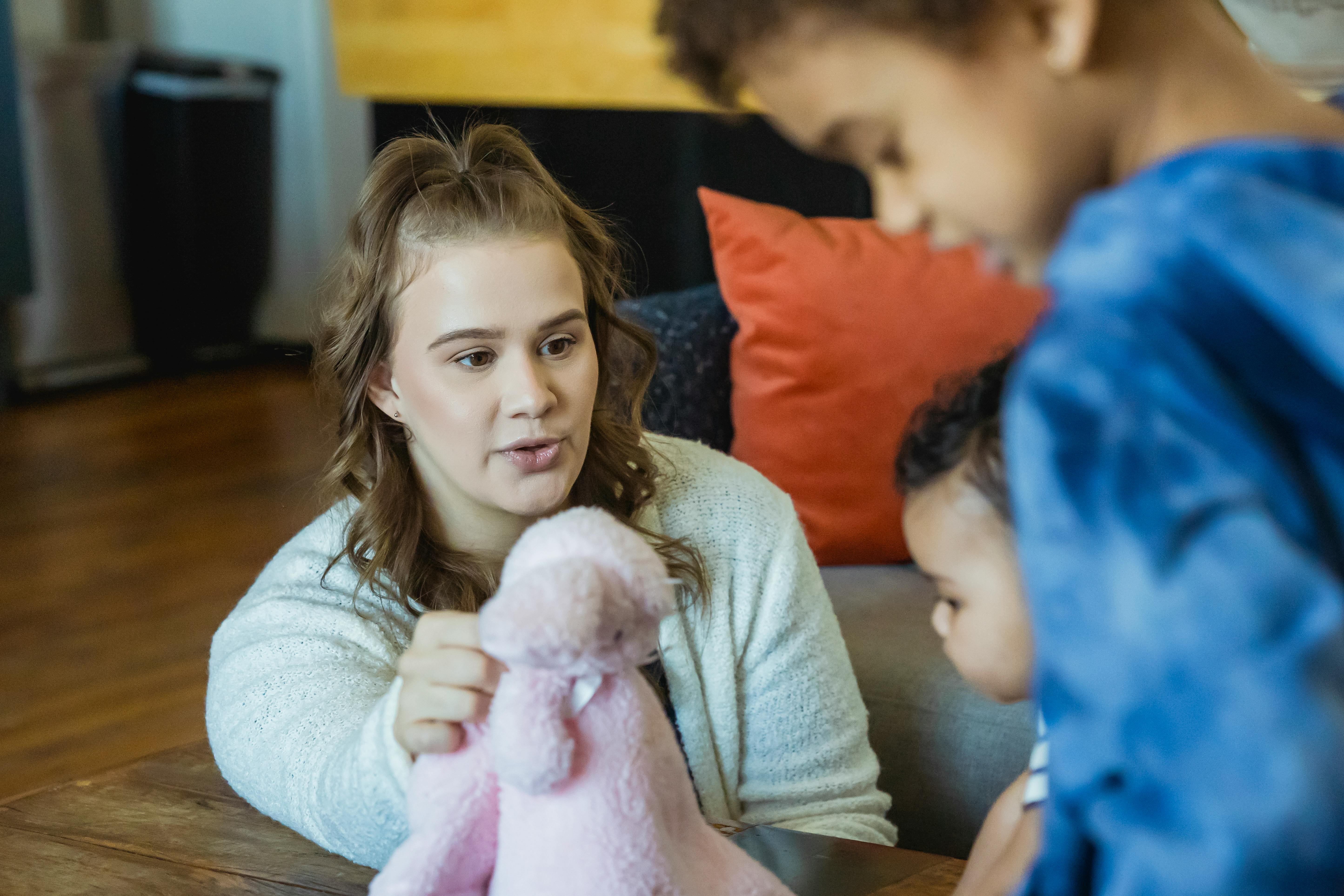 mother playing with crop ethnic children in house