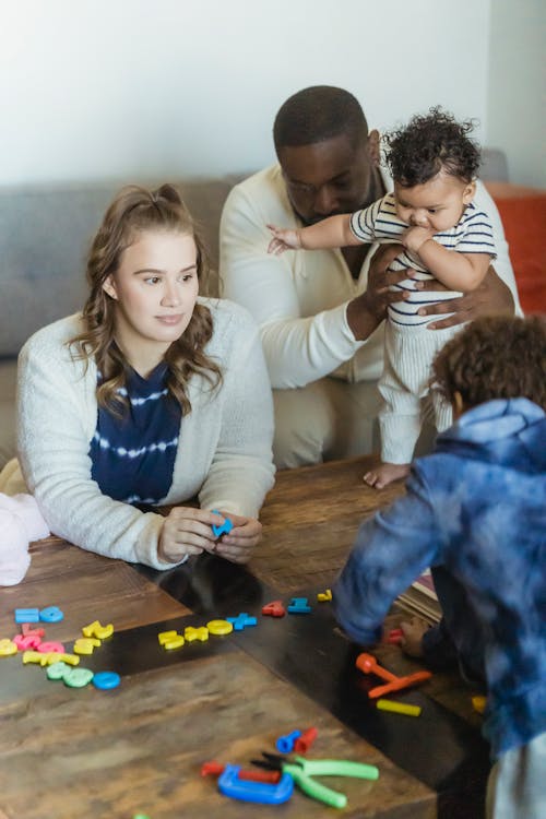 Unrecognizable multiracial family playing at table in room