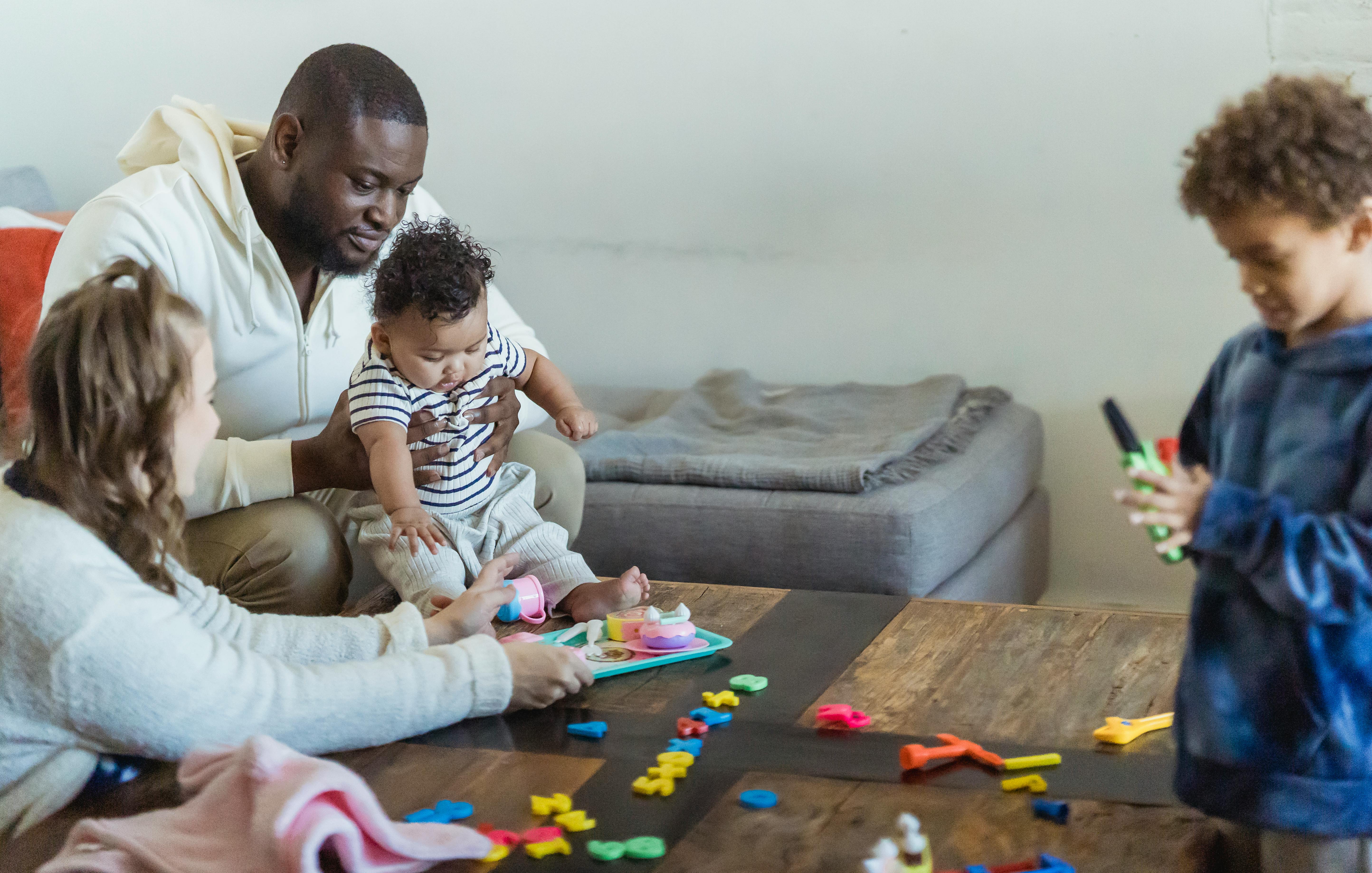 crop multiracial family playing with children at table in house