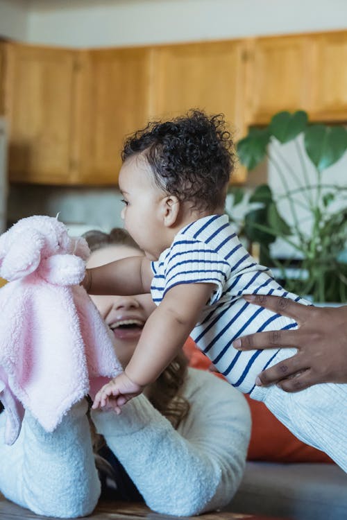 Free Unrecognizable mom playing with ethnic baby at home Stock Photo