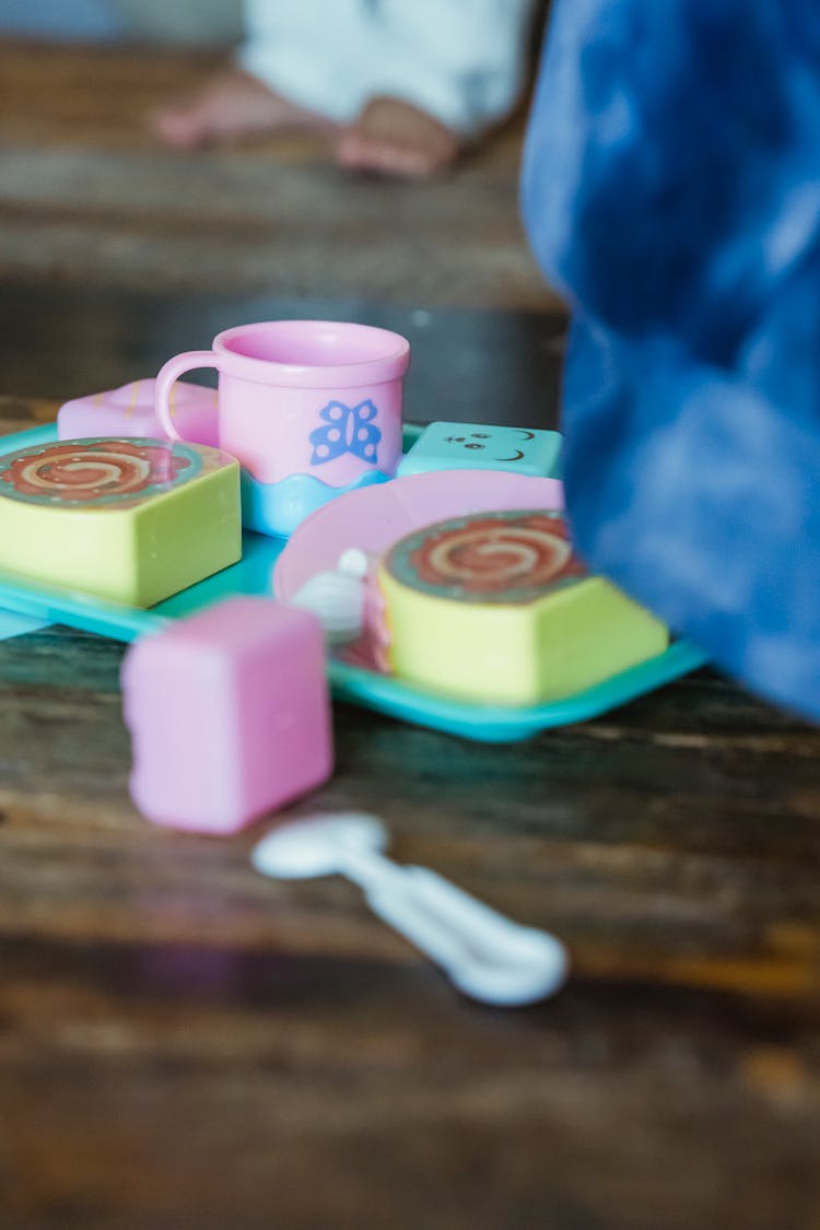 Toy Set With Decorative Rolls On Table Against Crop Baby