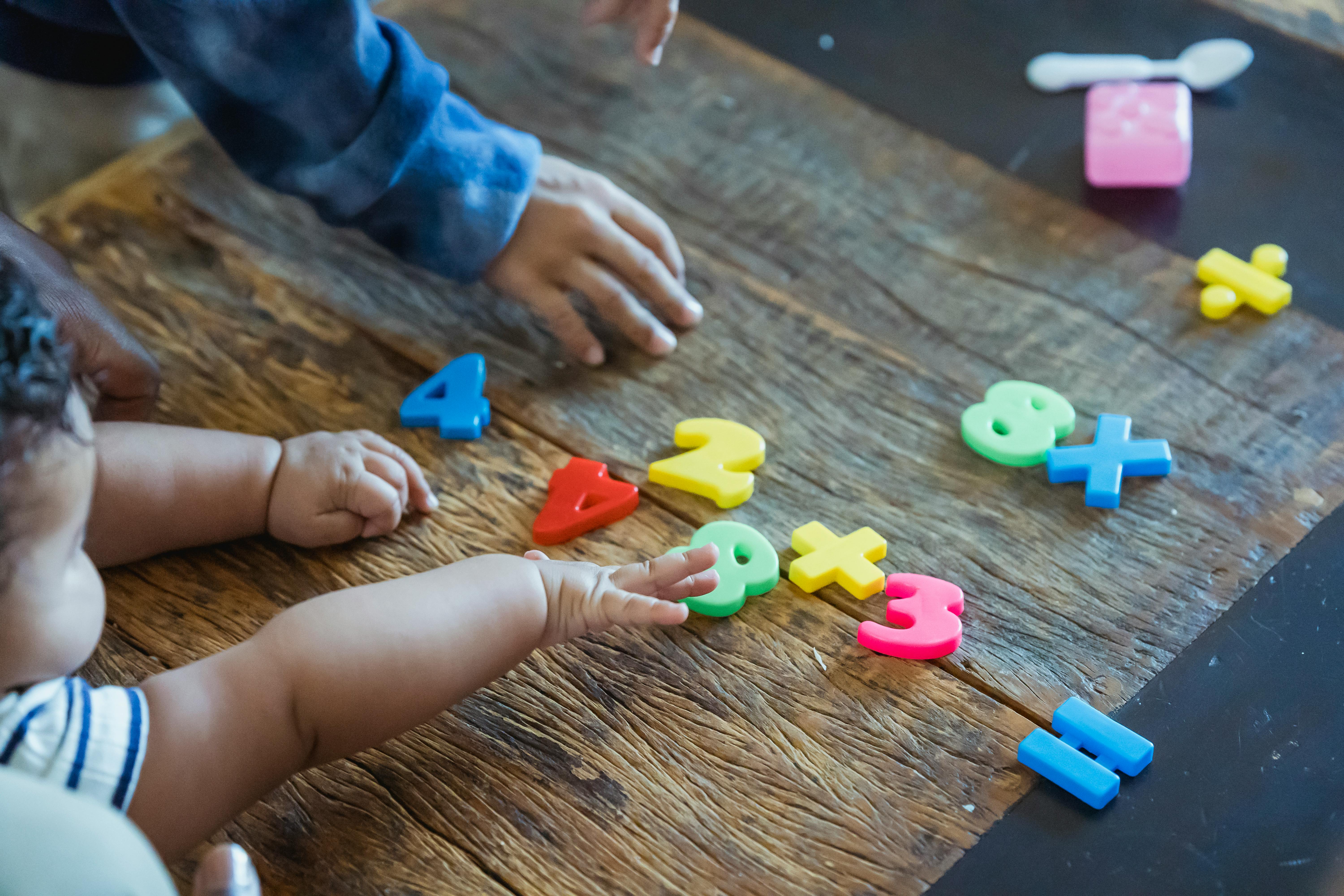 crop ethnic siblings playing with plastic toys at table