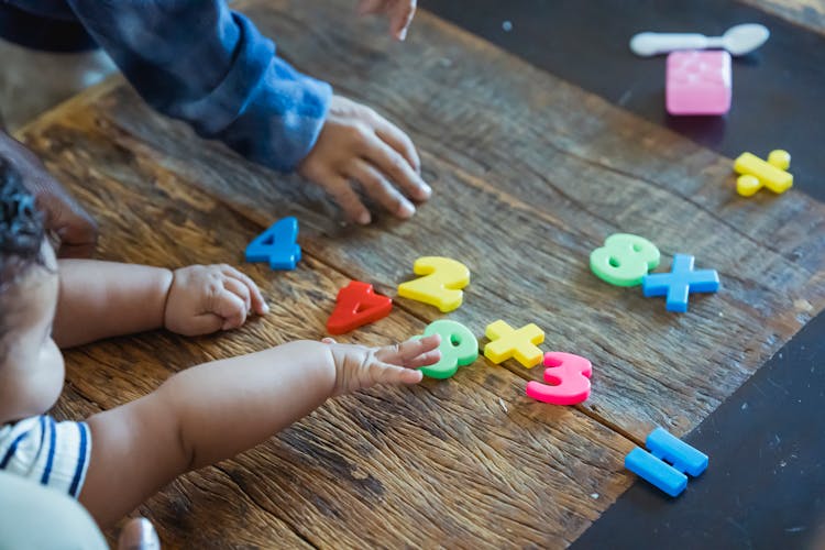 Crop Ethnic Siblings Playing With Plastic Toys At Table