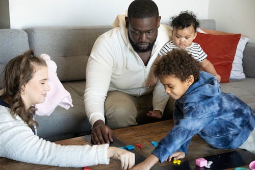 Crop multiethnic parents with children playing with toy numbers on sofa in house room