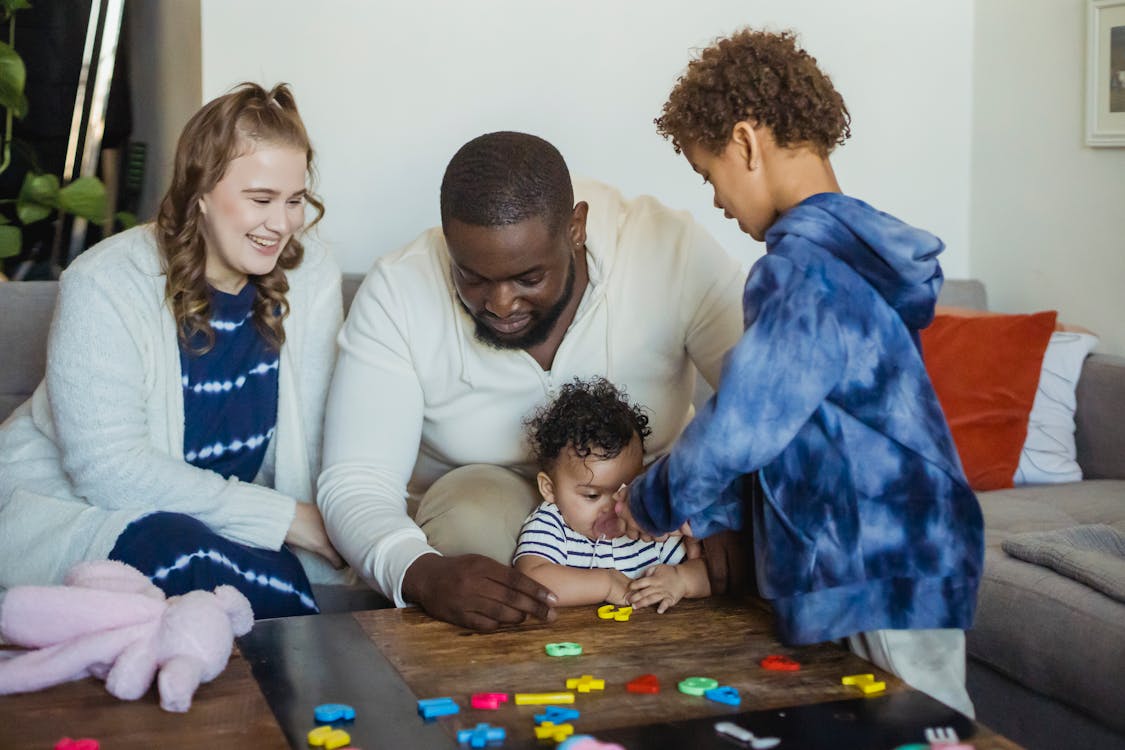 Free Happy multiracial family playing with little cute baby at table with colorful toys at home Stock Photo