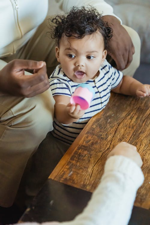 Black cute baby near father and child at table