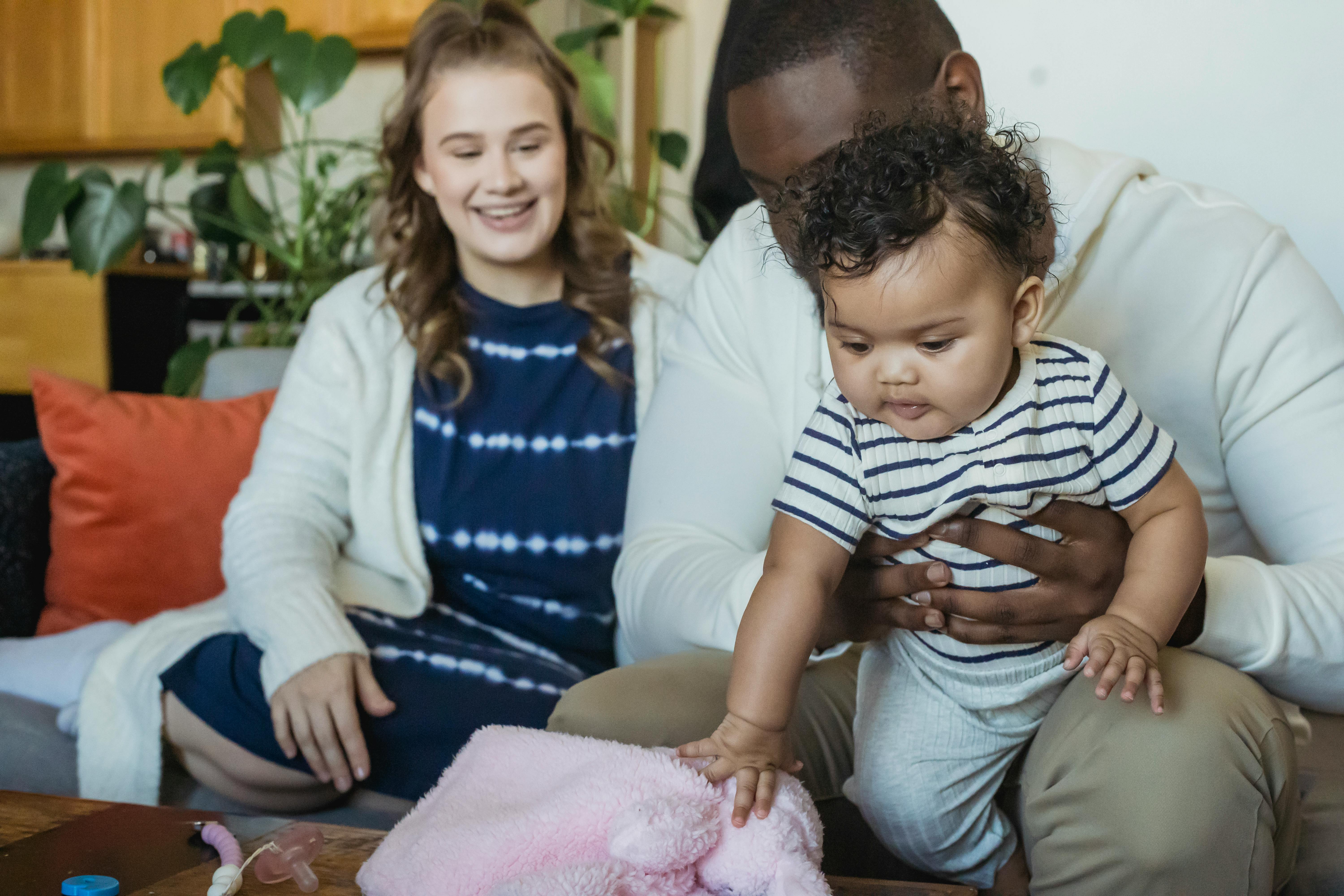 multiracial mother and father watching cute baby playing