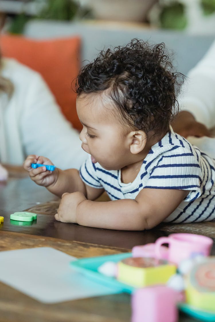 Little Black Cute Baby Playing At Wooden Table