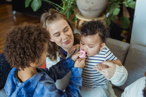 Free Black boy giving toy to infant in hands of mother Stock Photo