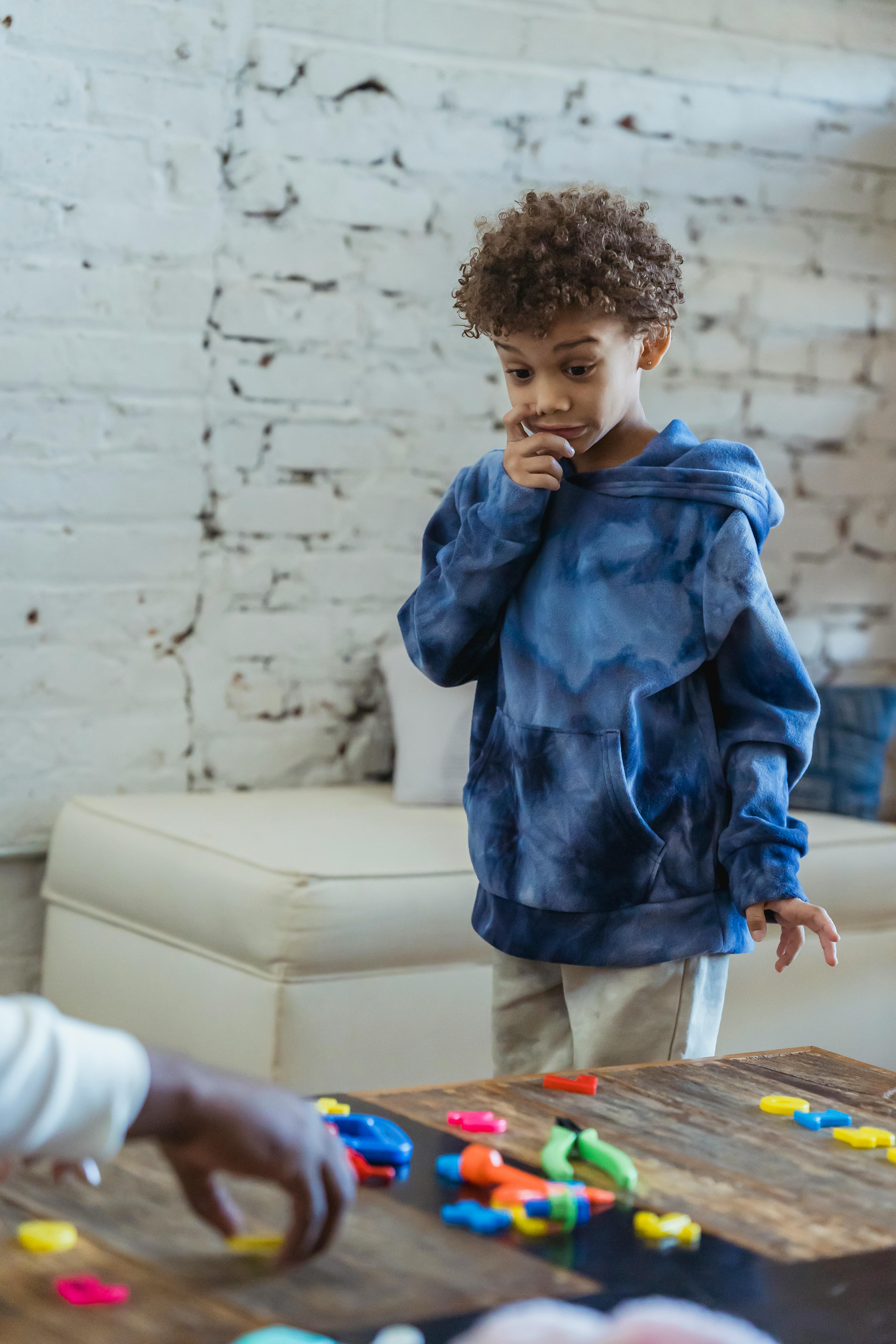 amazed black boy standing at table with toys