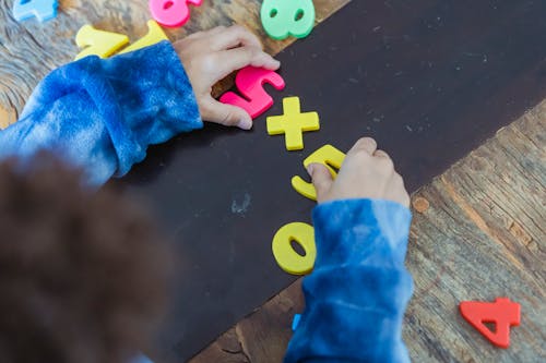 Free Ethnic boy solving mathematical example made of toy numbers Stock Photo
