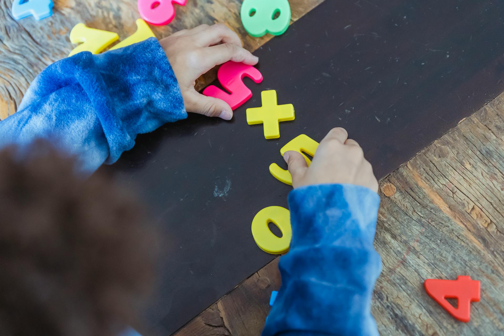 Ethnic boy solving mathematical example made of toy numbers