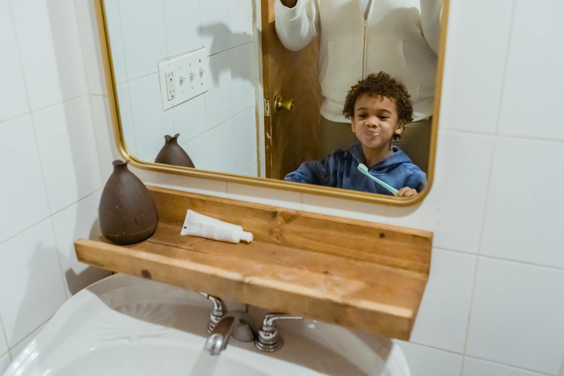 Black boy brushing teeth with unrecognizable father