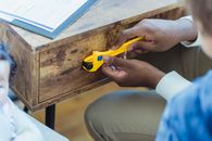 Anonymous African American father with toy adjustable wrench tightening up knob on wooden drawer near faceless son while spending time together