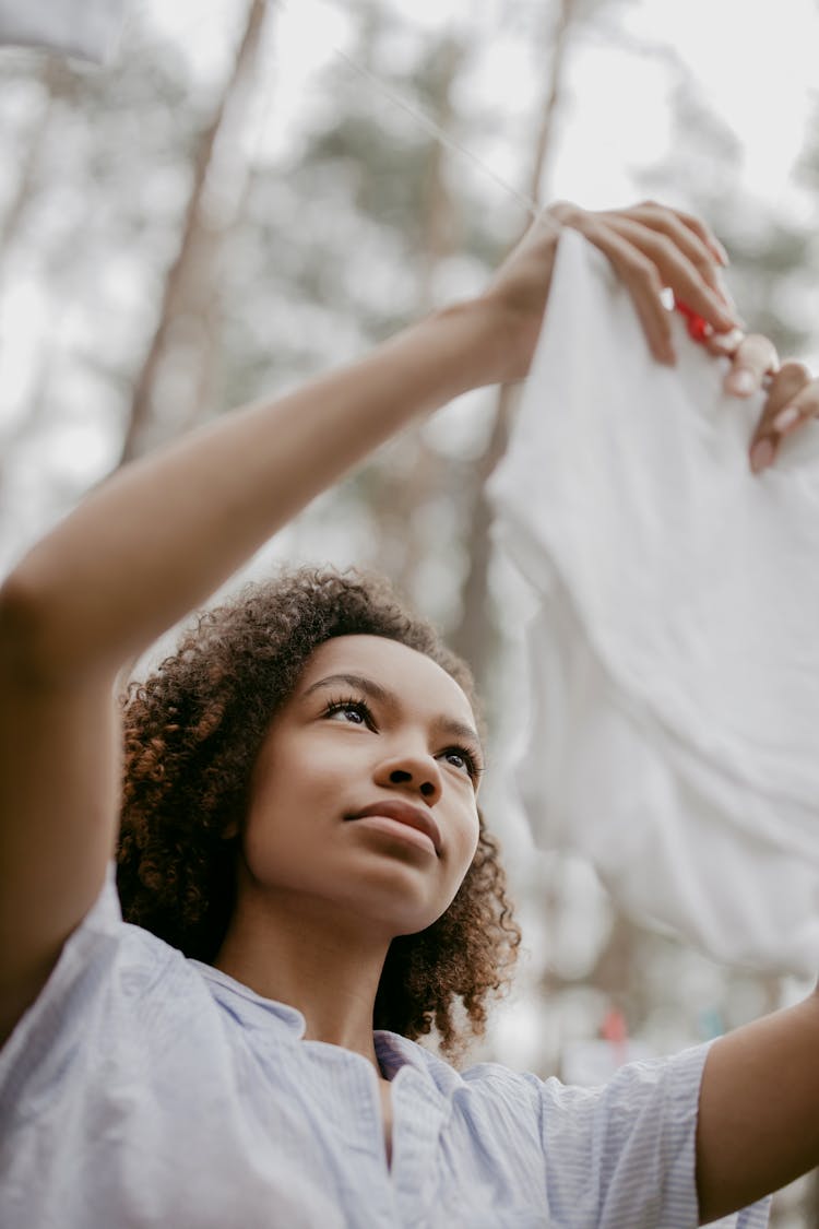 Low-Angle Shot Of A Woman Hanging The White Cloth On Clothesline