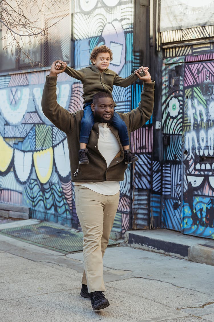 Black Father Walking With Son On Shoulders