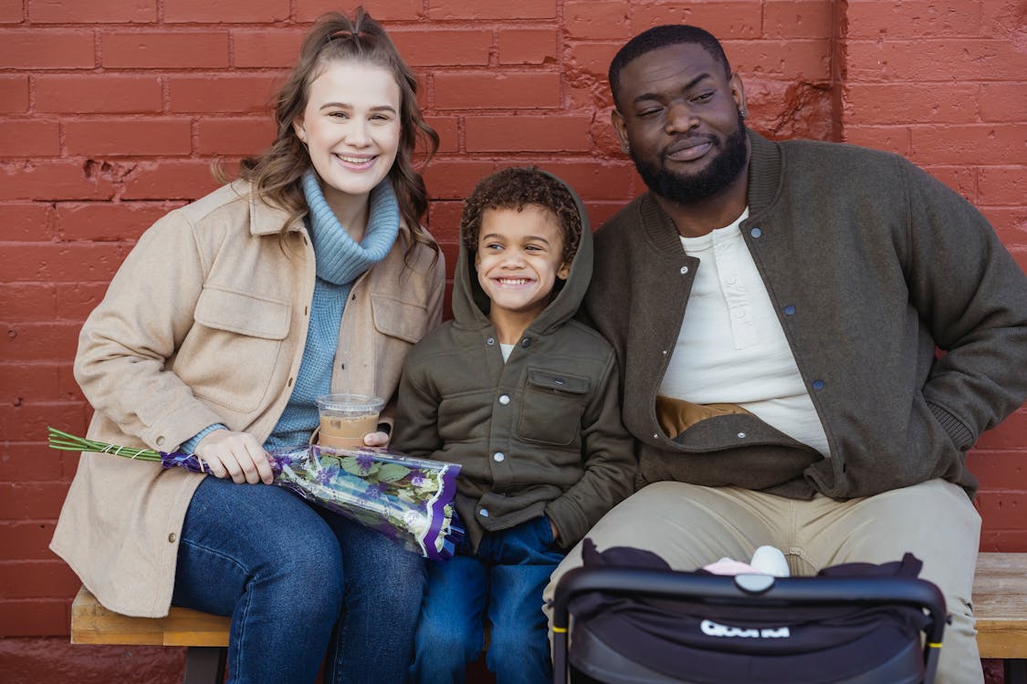 Cheerful diverse family sitting on street bench