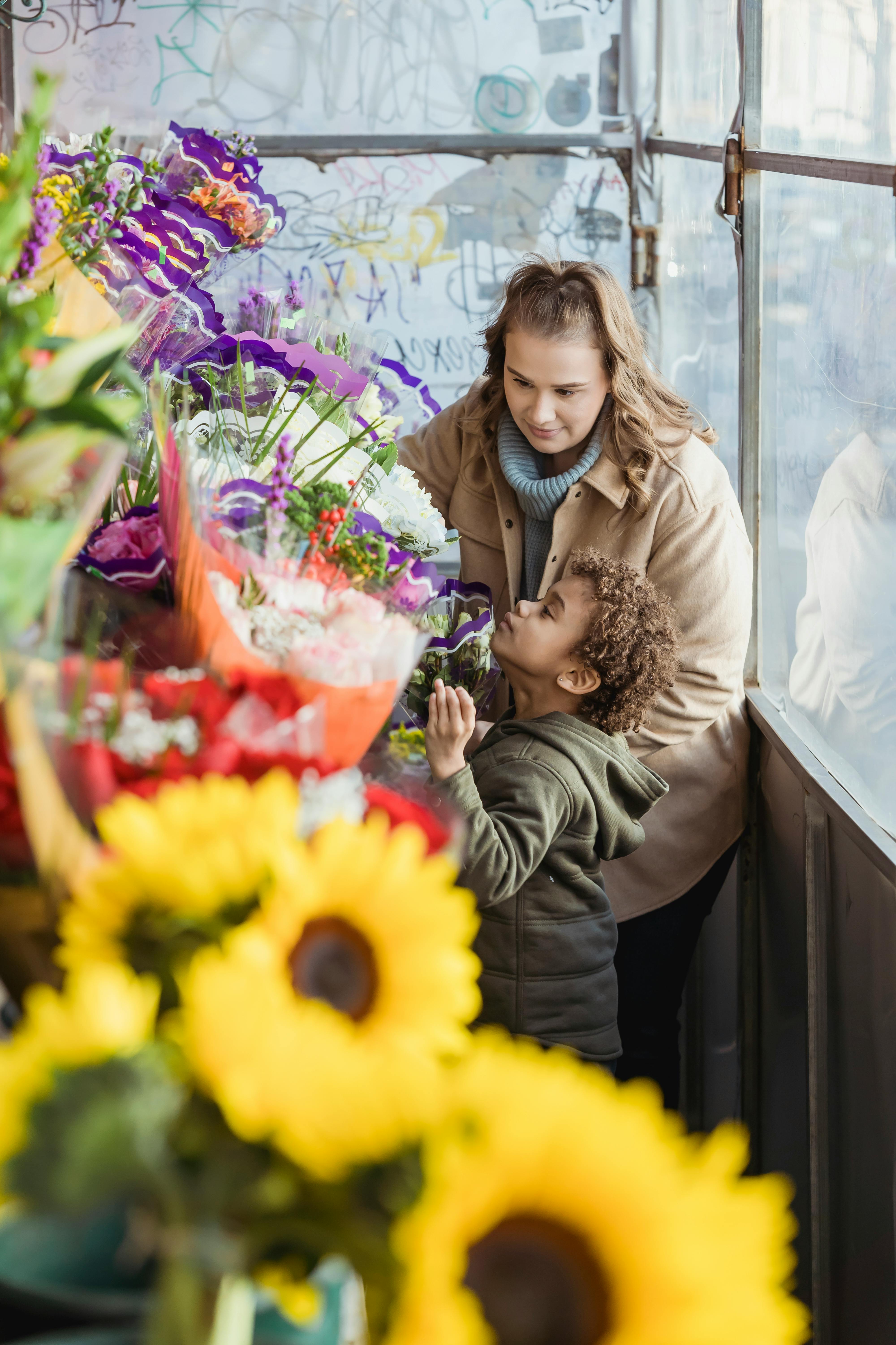 diverse mother and son choosing flowers in floral shop