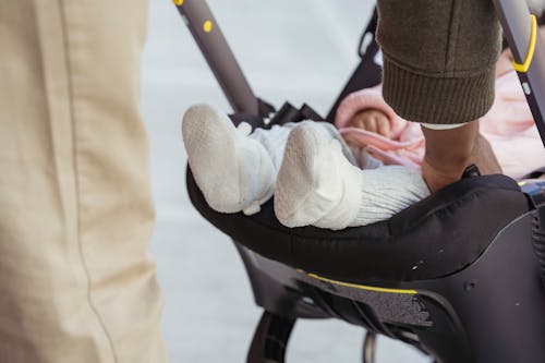 Crop unrecognizable black father caressing newborn baby in stroller