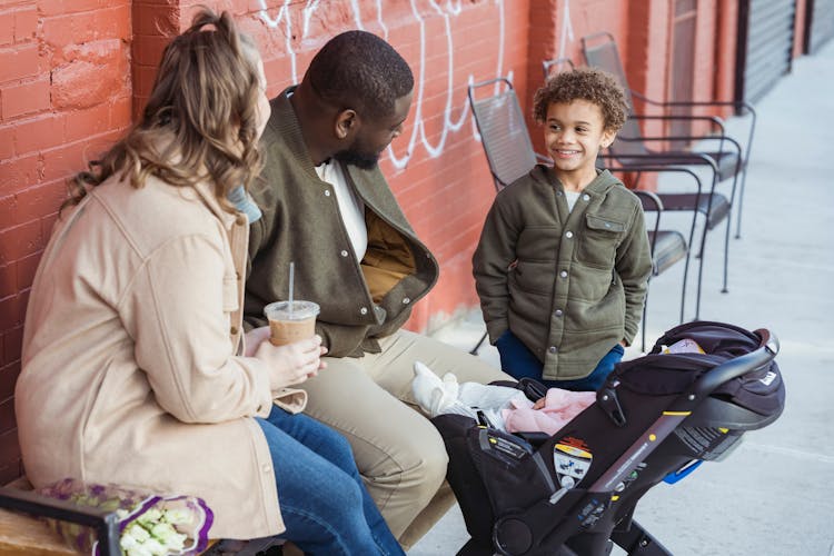 Happy Diverse Family Chatting And Sitting On Street Bench