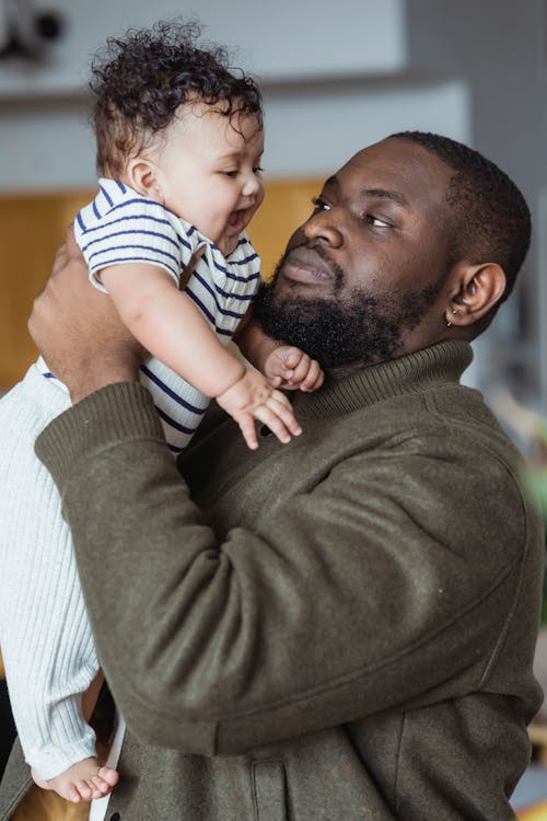 Free Black father embracing adorable baby with mouth opened Stock Photo