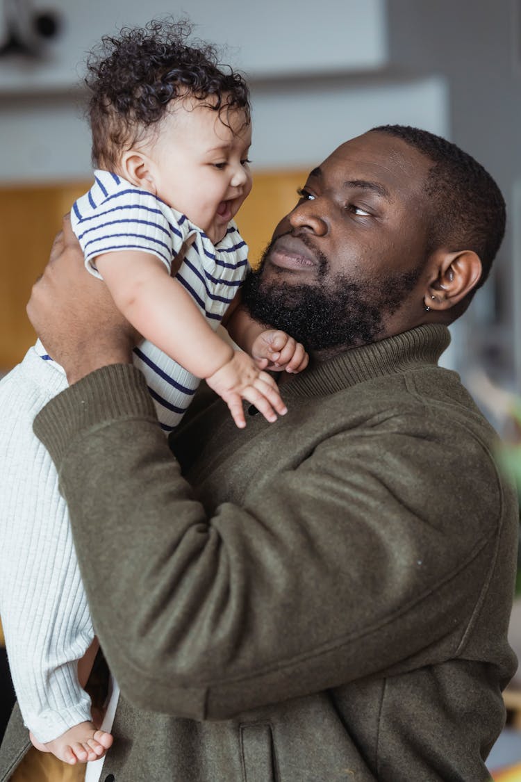 Black Father Embracing Adorable Baby With Mouth Opened