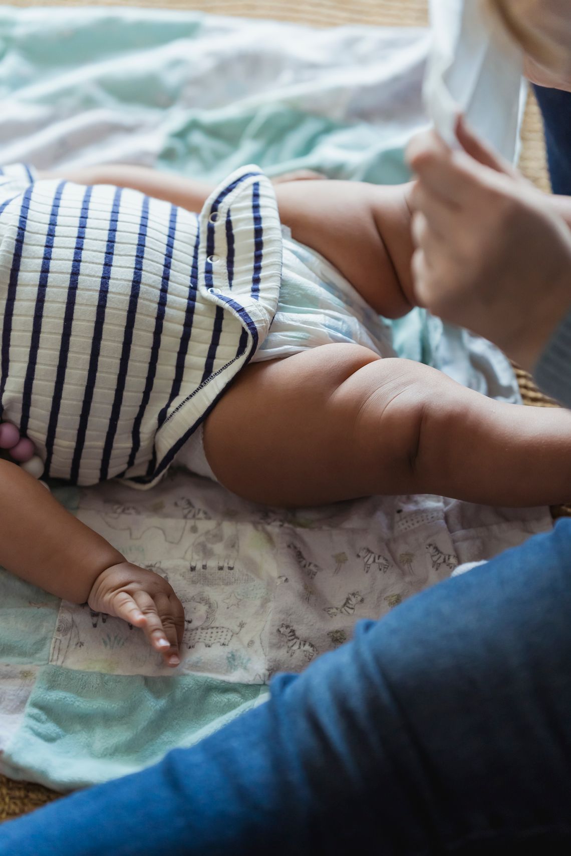 Mother gently changing her baby's diaper on a soft blanket