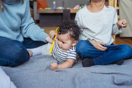 Free Small African American infant with toy in hand lying near crop brother and mom sitting on plaid Stock Photo