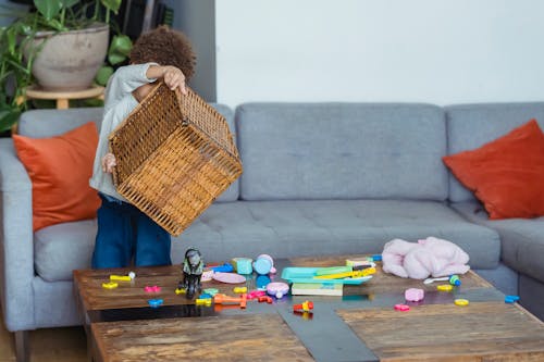 Little boy turning over wicker basket with plastic toys