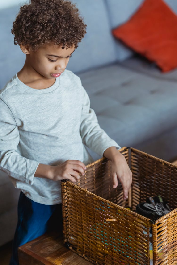 Little Boy Looking For Toys In Wicker Box