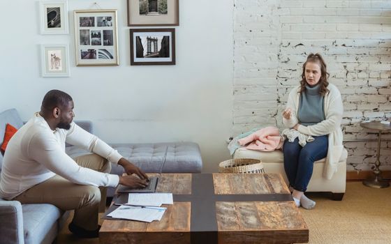 Full body of multiracial couple sitting in living room and sorting things out