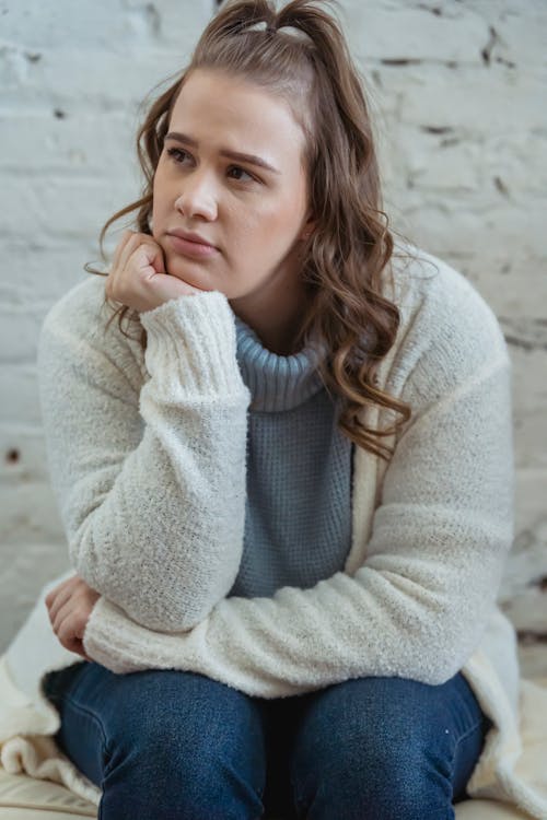 Free Young woman supporting head with hand and looking away Stock Photo