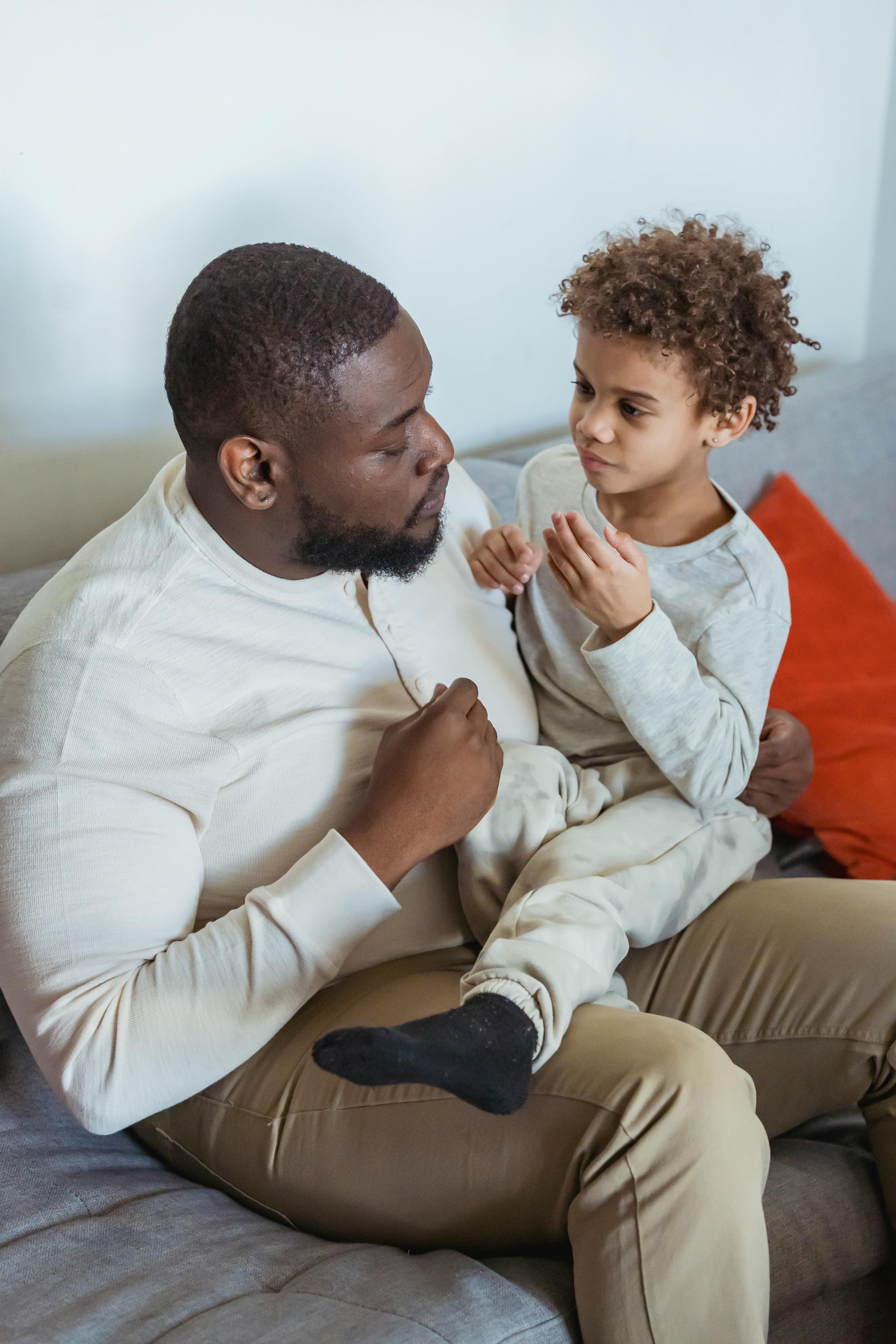 black man talking with son on knees