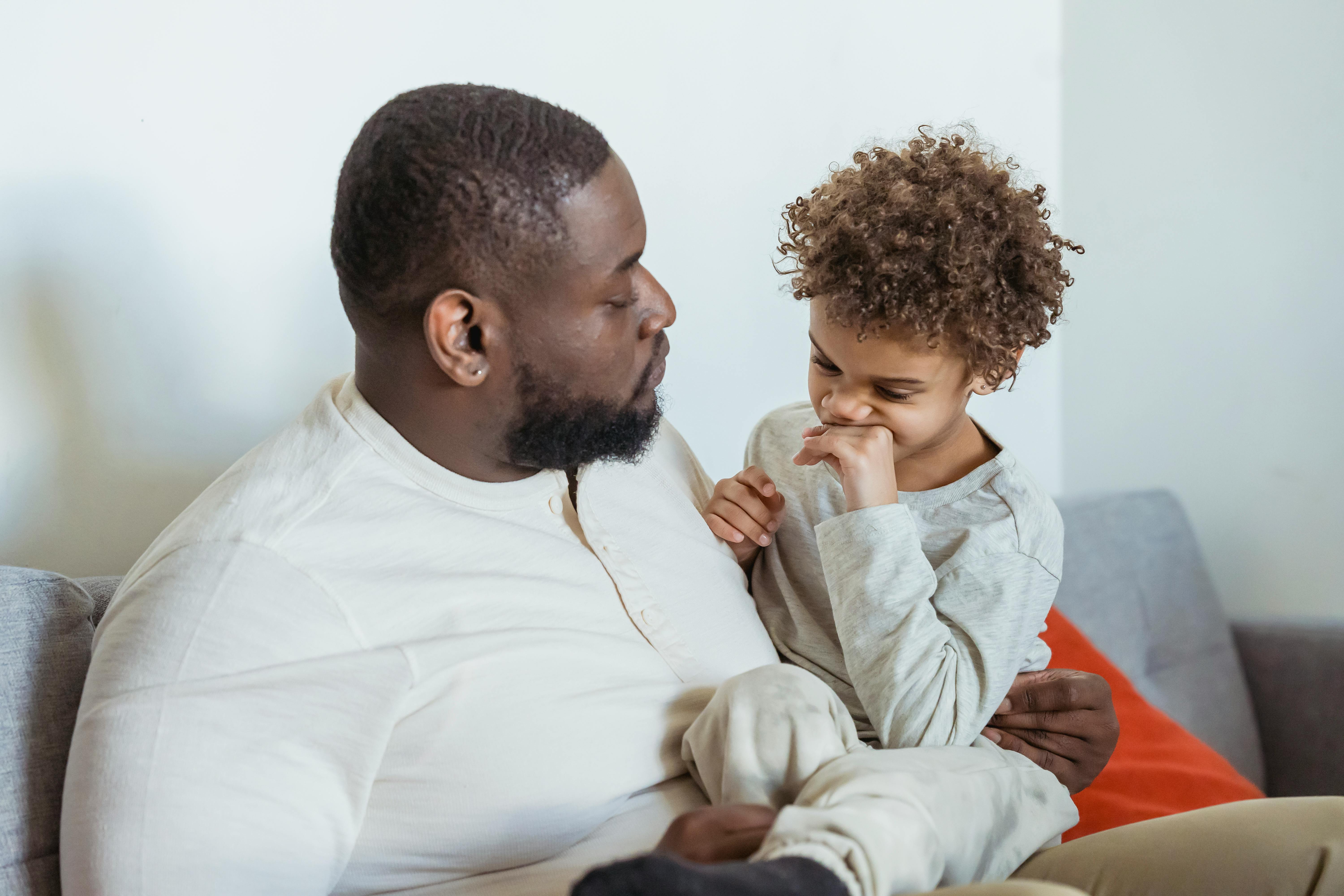 serious black father with black boy on knees