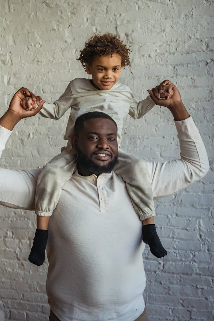 Cheerful Black Father With Adorable Son On Shoulders