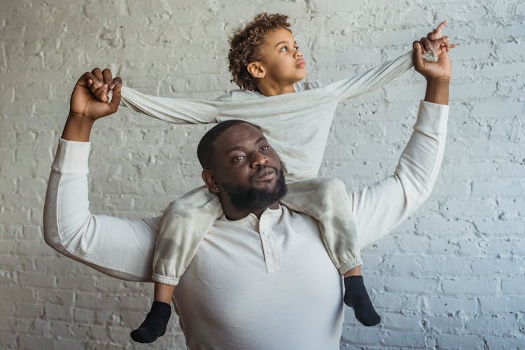 Serious Black Father With Son On Shoulders