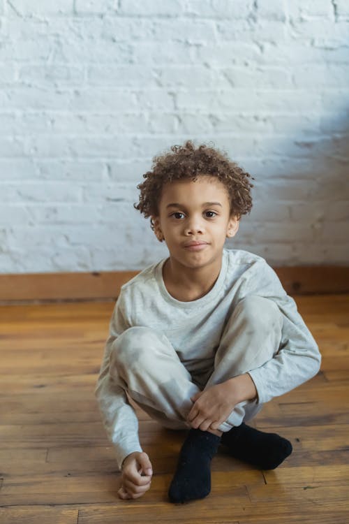 Adorable black boy sitting in room