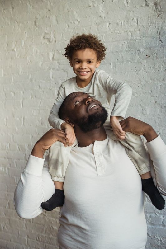 A father playfully carrying his son on his shoulders