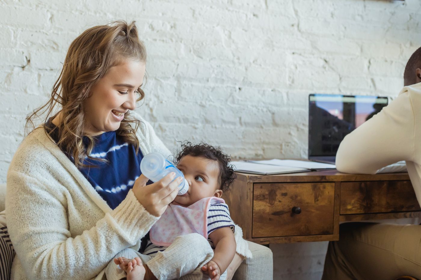 Mother gently feeding her baby with a bottle at home
