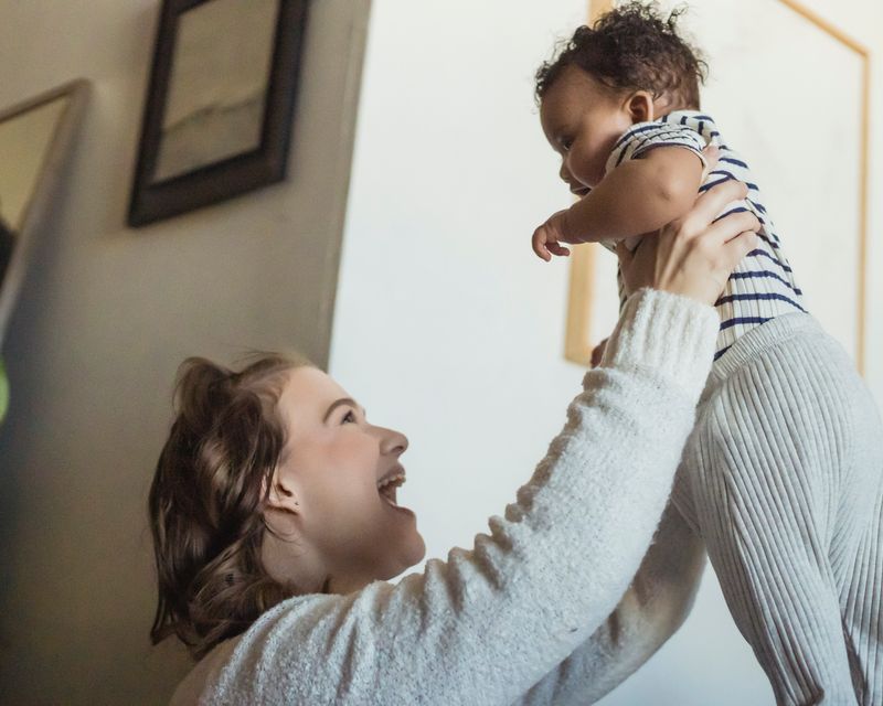 Mom laughing while lifting her toddler
