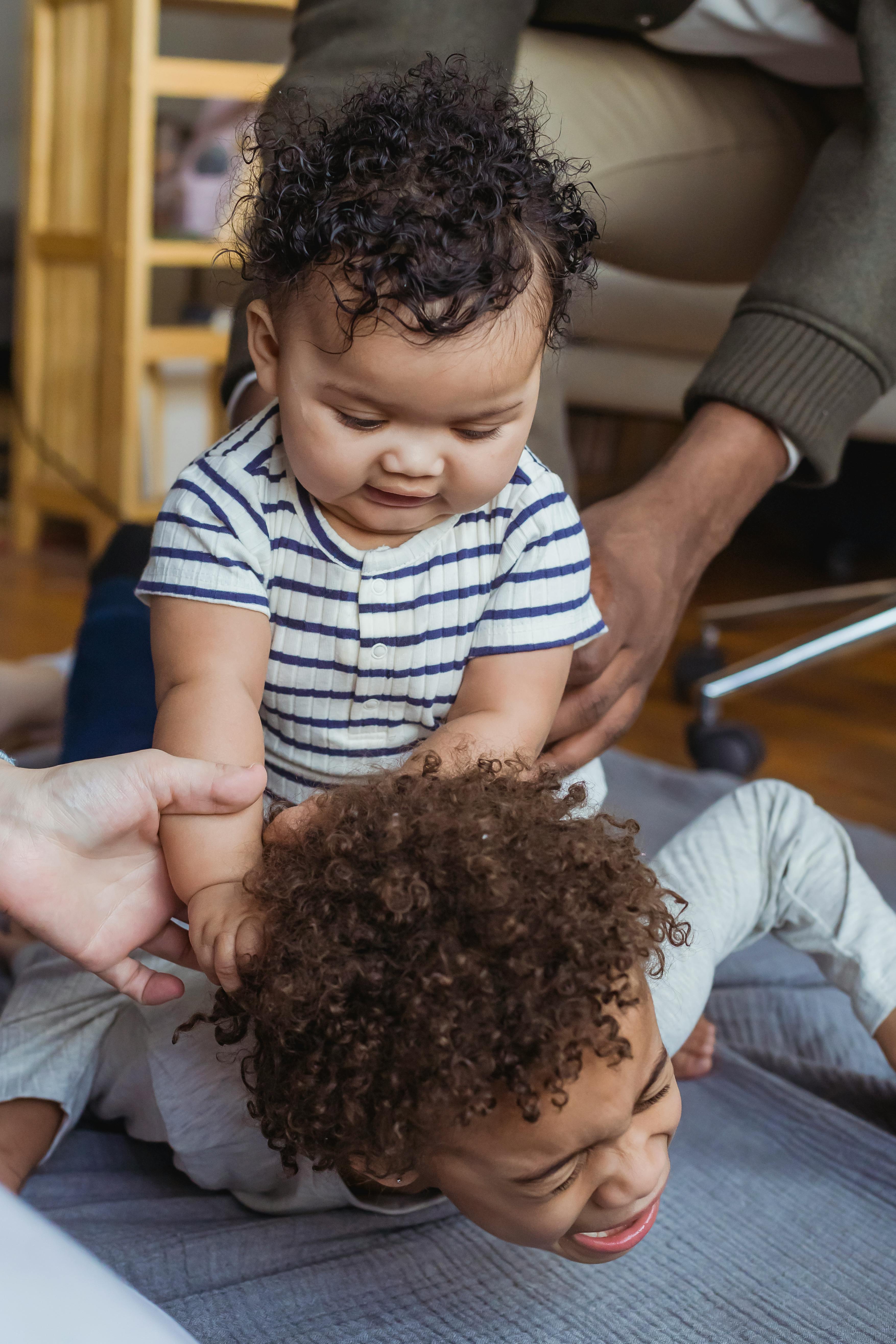 multiethnic children near parents on blanket on floor