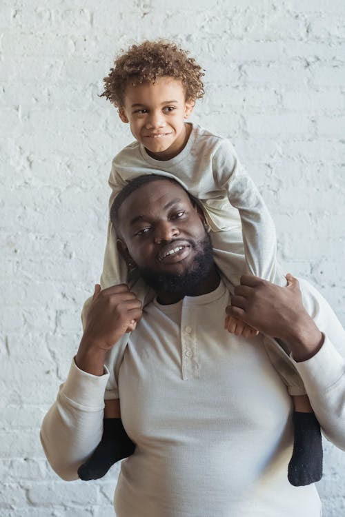 Black male carrying kid on shoulders