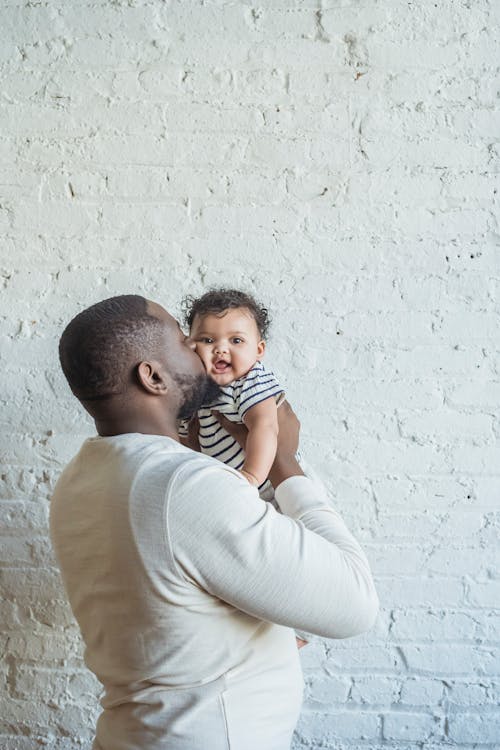 Black father kissing baby in arms
