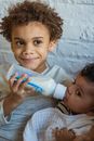 Charming African American boy feeding cute little baby from bottle