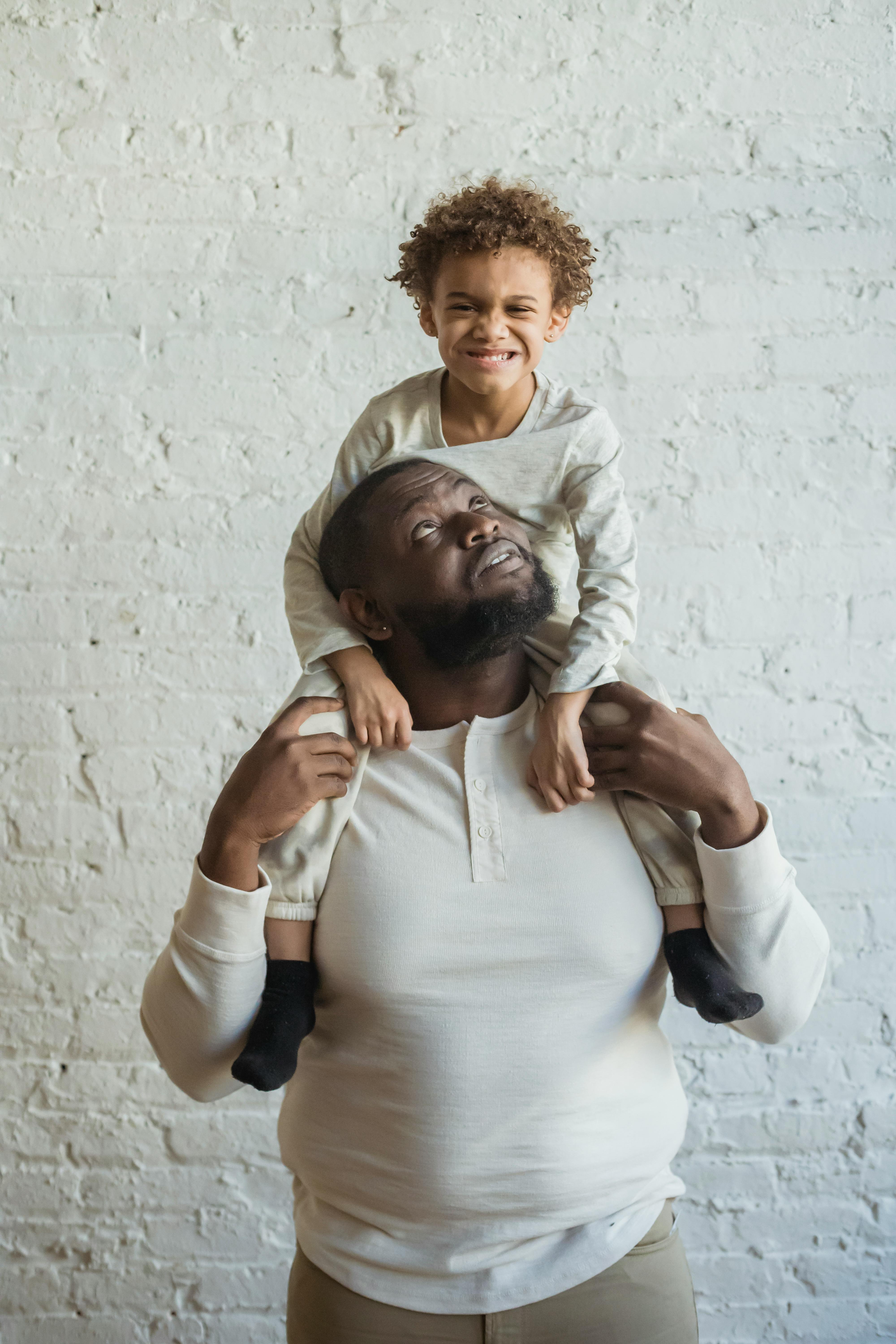 Black father holding child on shoulders · Free Stock Photo