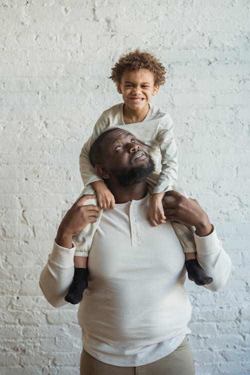 Black father holding child on shoulders