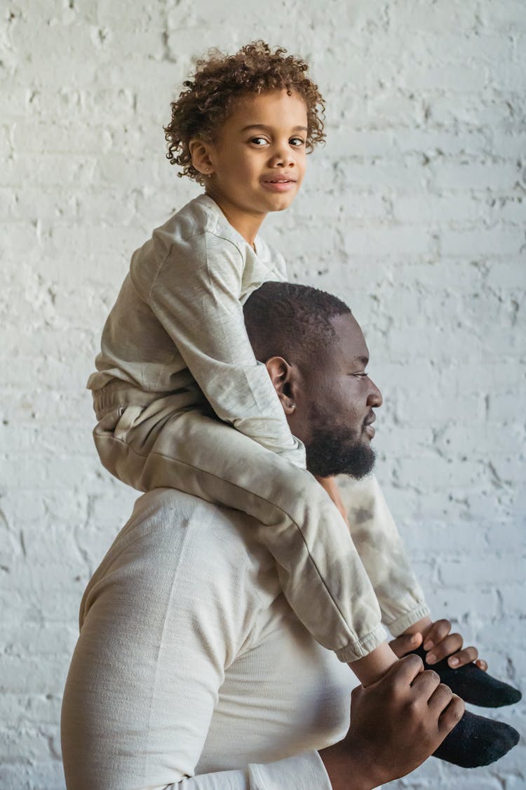 Black Man Carrying Cute Son On Shoulders